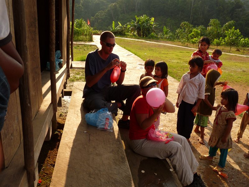 Blowing up balloons for the children in a minority village